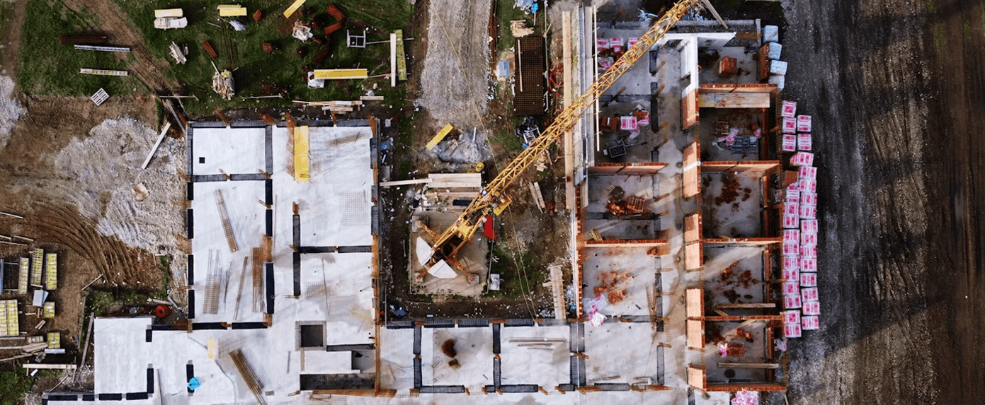 Aerial view of a commercial construction site with foundations under way and a tower crane